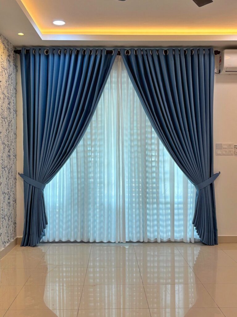 Blue draped curtains with tie-backs and sheer white under-curtains in a living room.