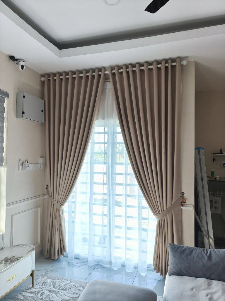 Beige pleated curtains and sheer white liners in a neutral living room setting.