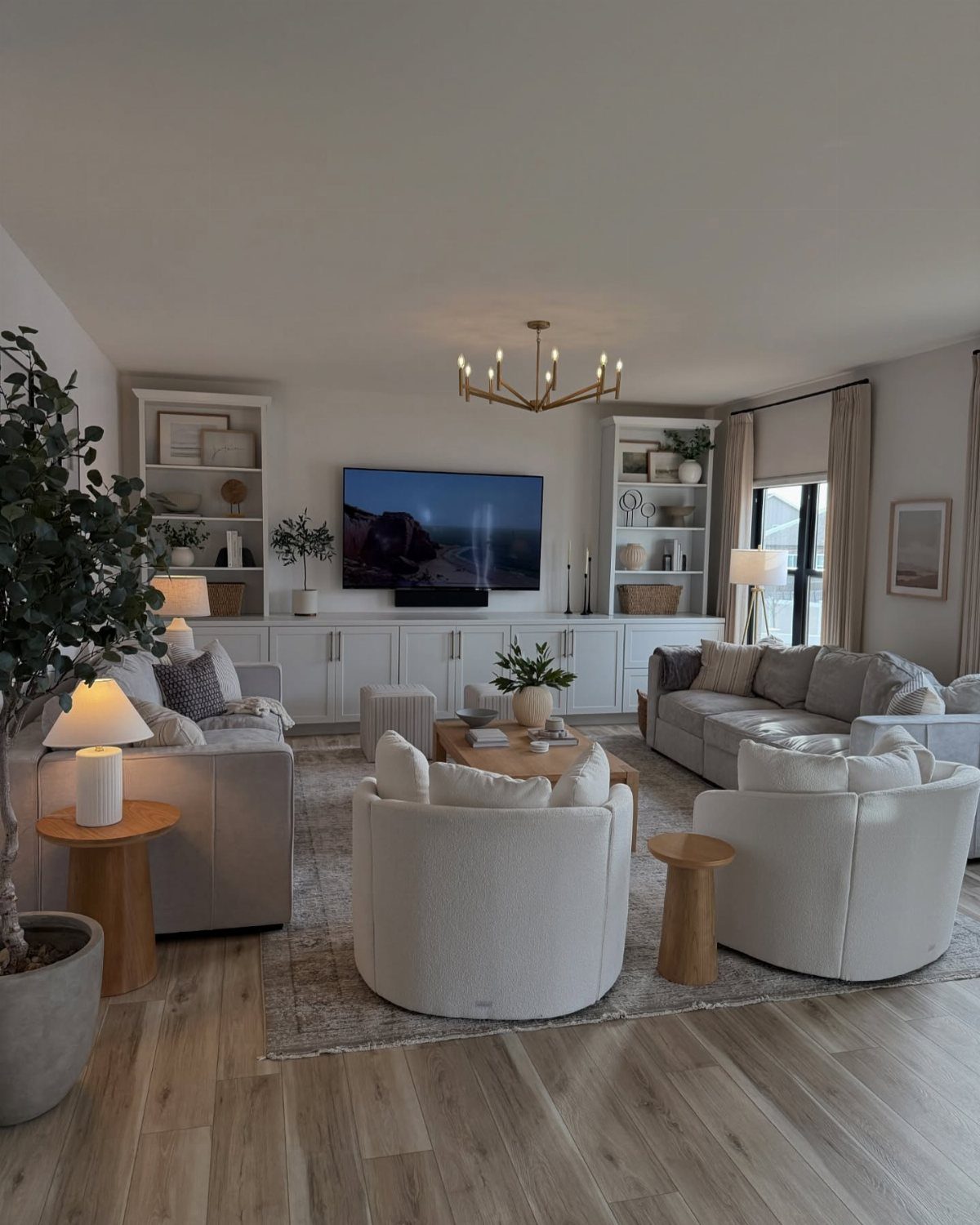Modern family room with white swivel chairs, grey sectional, and built-in white cabinetry.