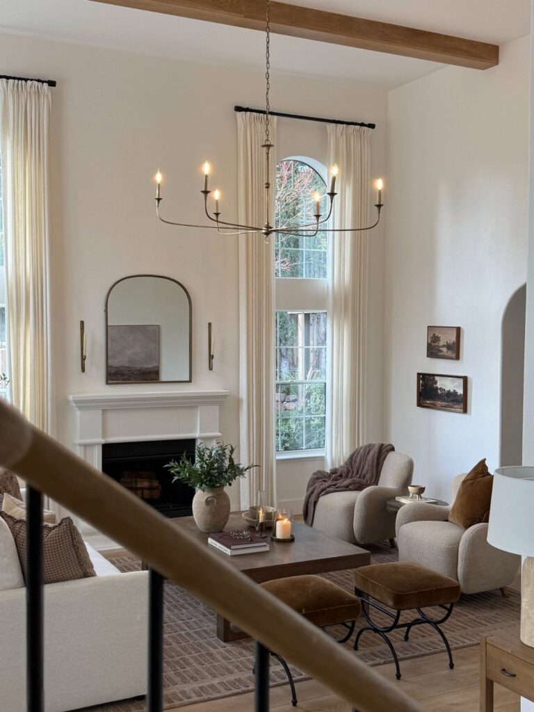 Large black metal chandelier hanging in a bright, rustic white living room.