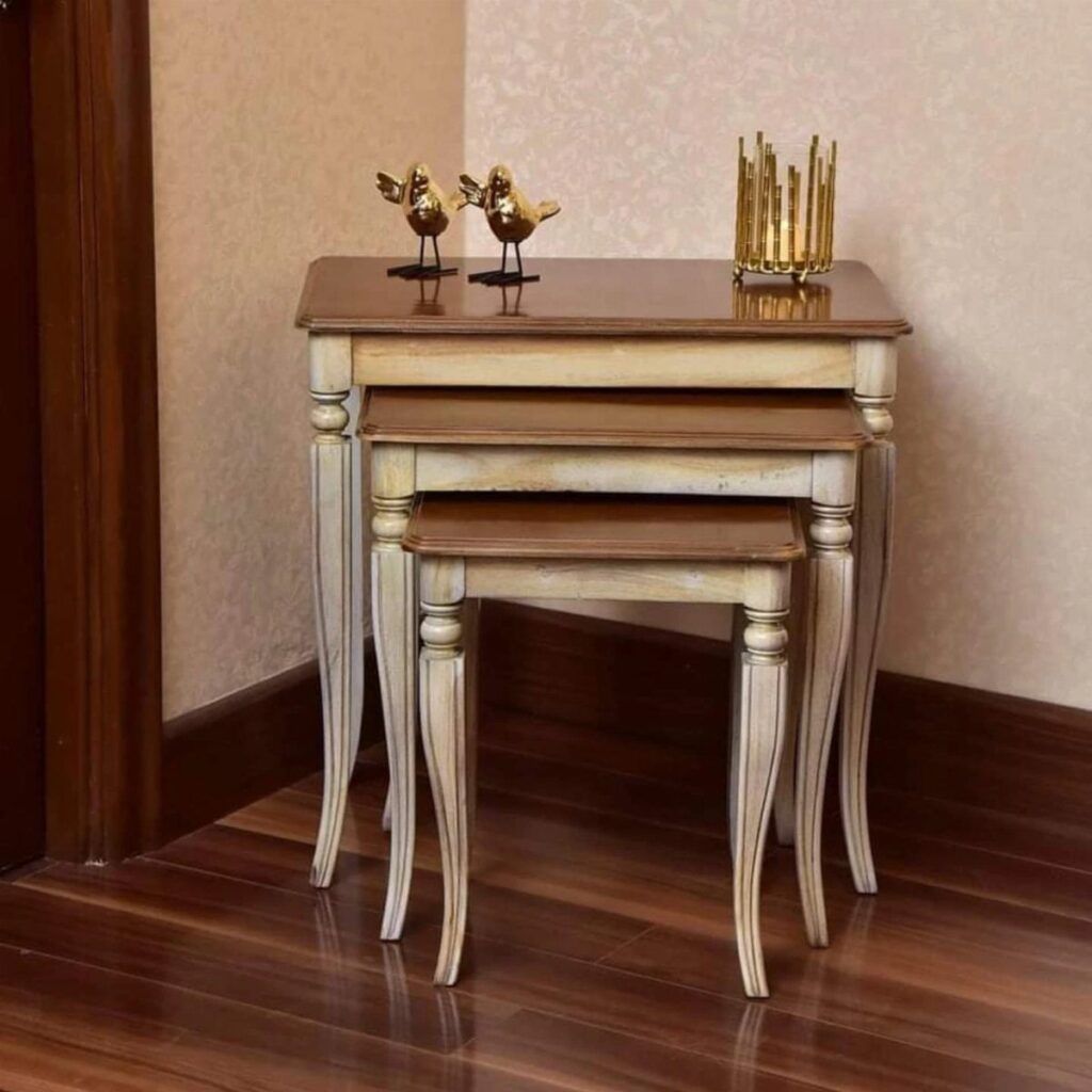 Three nesting tables with brown tops and cream legs on a dark wood floor.