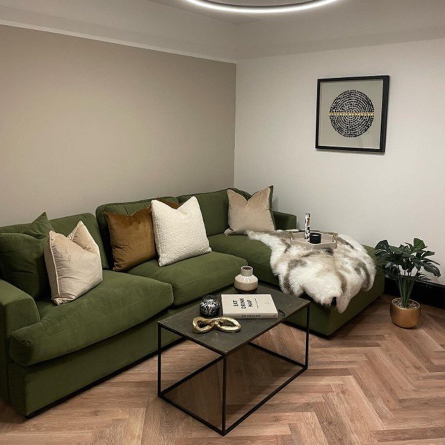 Olive green sectional sofa with neutral pillows in a modern living room setting.