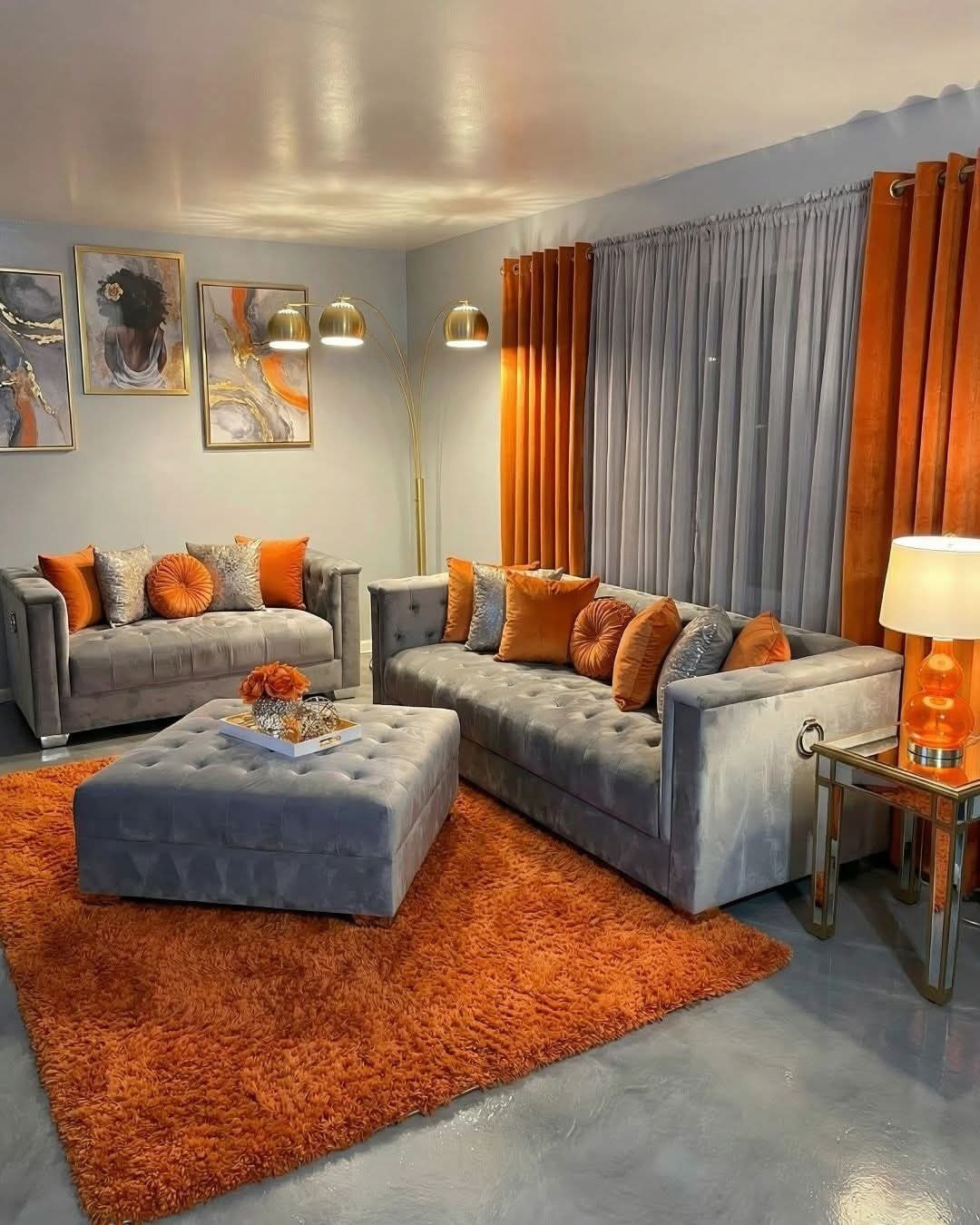 Grey velvet couches and ottoman with orange accents in a modern living room