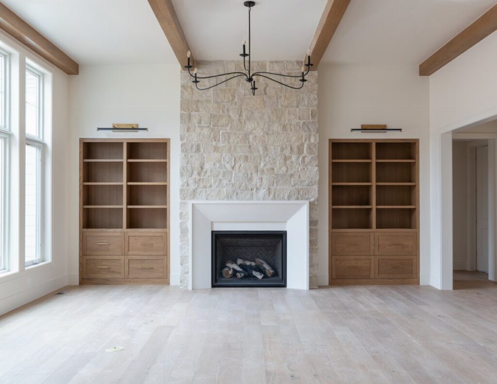 Light wood built-in bookshelves flanking a stone fireplace in a bright living room