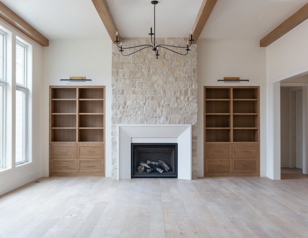 Light wood built-in bookshelves flanking a stone fireplace in a bright living room