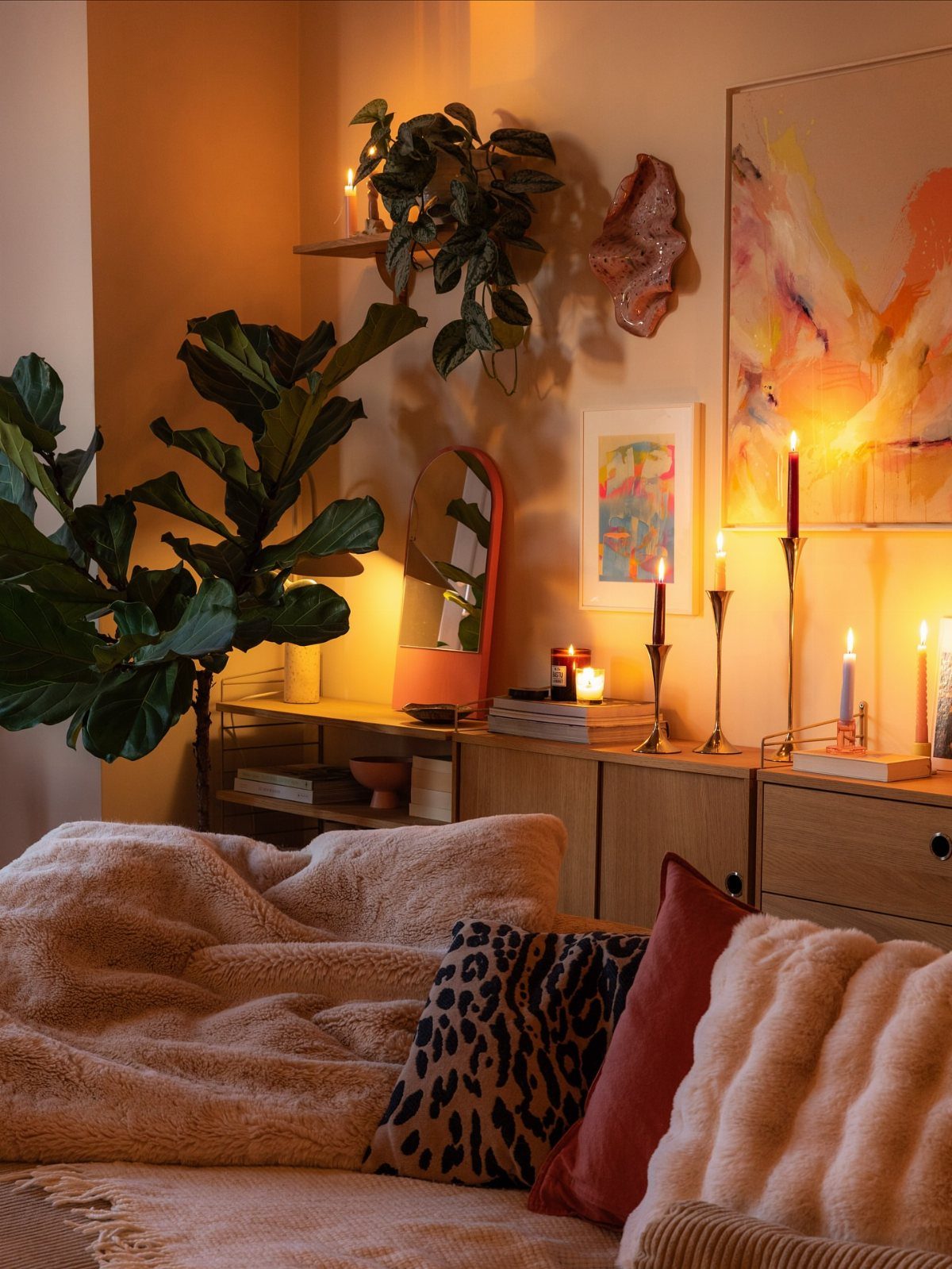 Cozy living room with plush blankets, leopard print pillows, and warm candlelight.