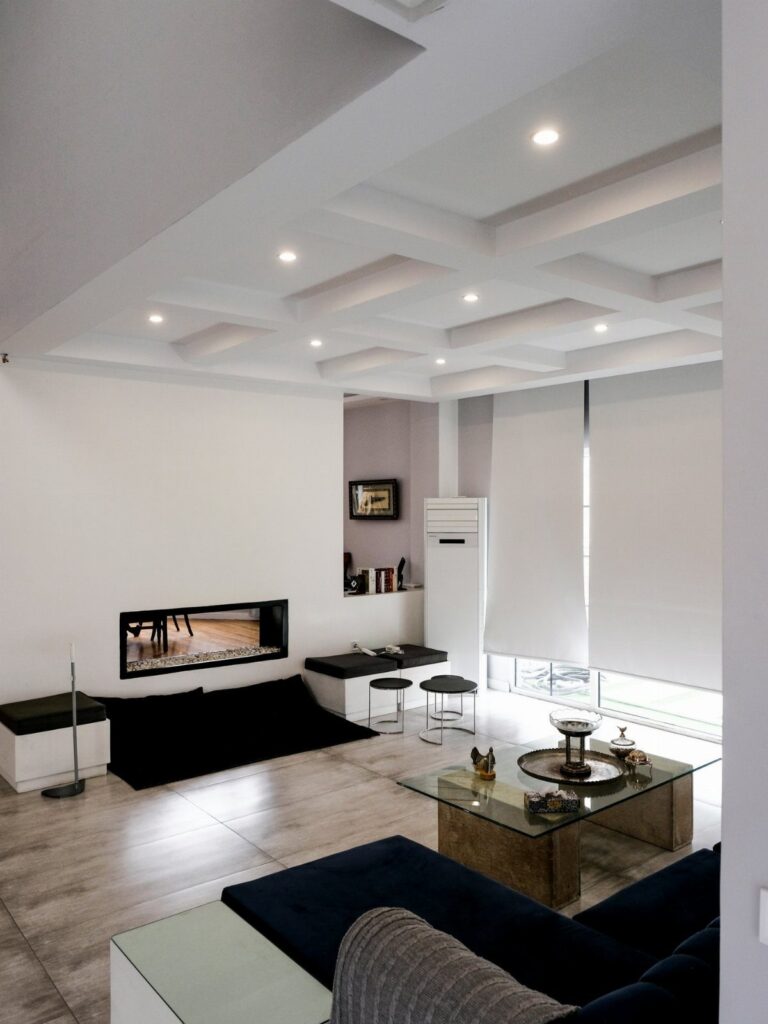 Modern living room with recessed lighting installed in a white coffered ceiling.