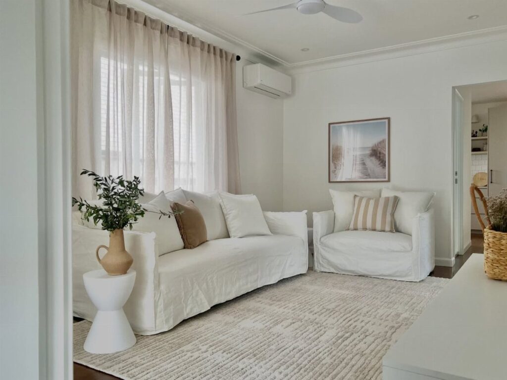 White sofas with front legs resting on a light grey textured living room rug