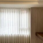 White sheer curtains hanging in a modern room next to a slatted wall.