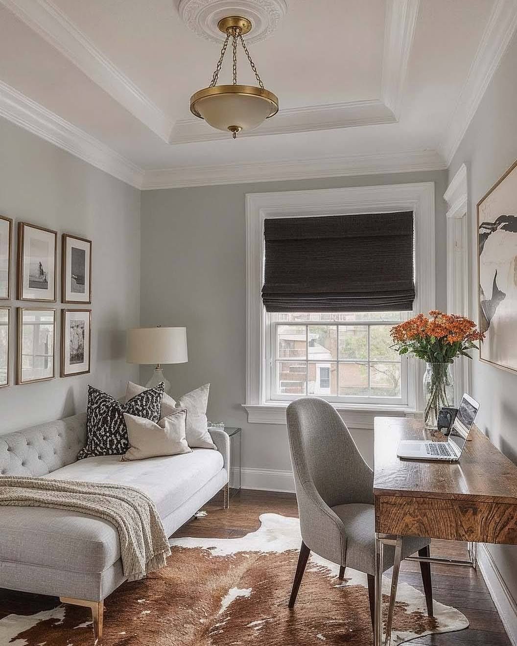 Light grey tufted daybed and wooden desk in a modern home office setting.