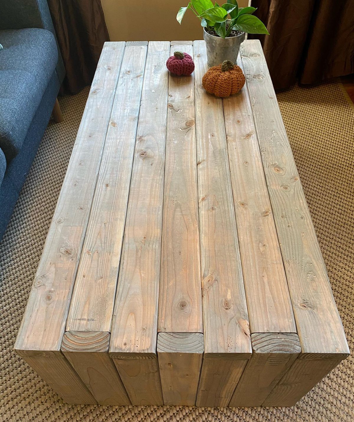 Pallet wood coffee table with decorative pumpkins and a small potted plant.