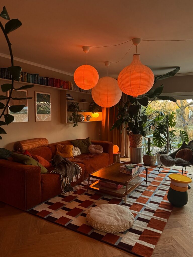Burnt orange-red couch in a living room with glowing orange paper lanterns.