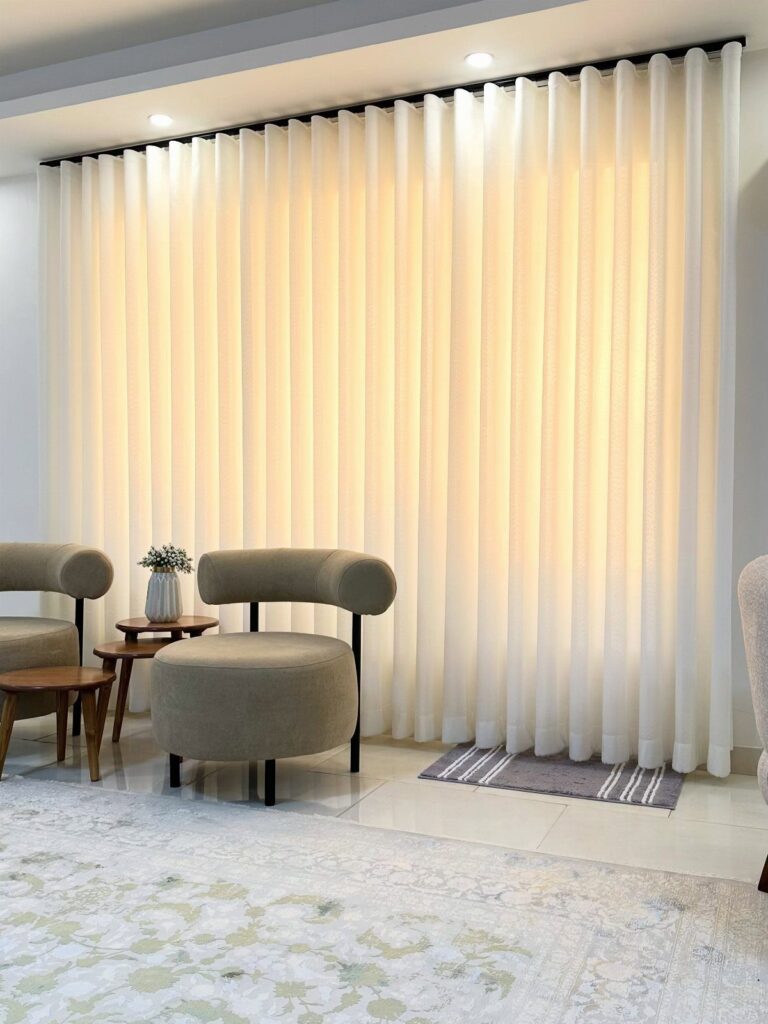 White sheer curtains covering a window in a room with beige armchairs.