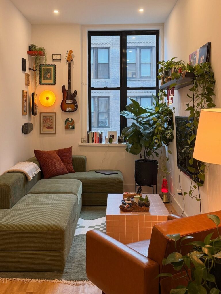 Small living room with green sectional sofa, leather chair, and indoor plants.
