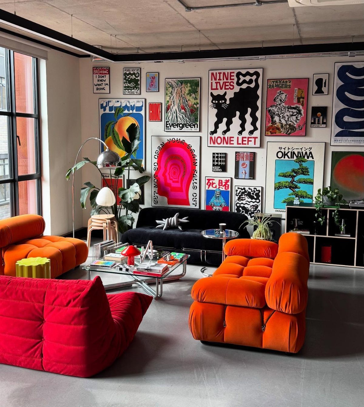 Gallery wall of colorful art prints above a black couch in a modern room