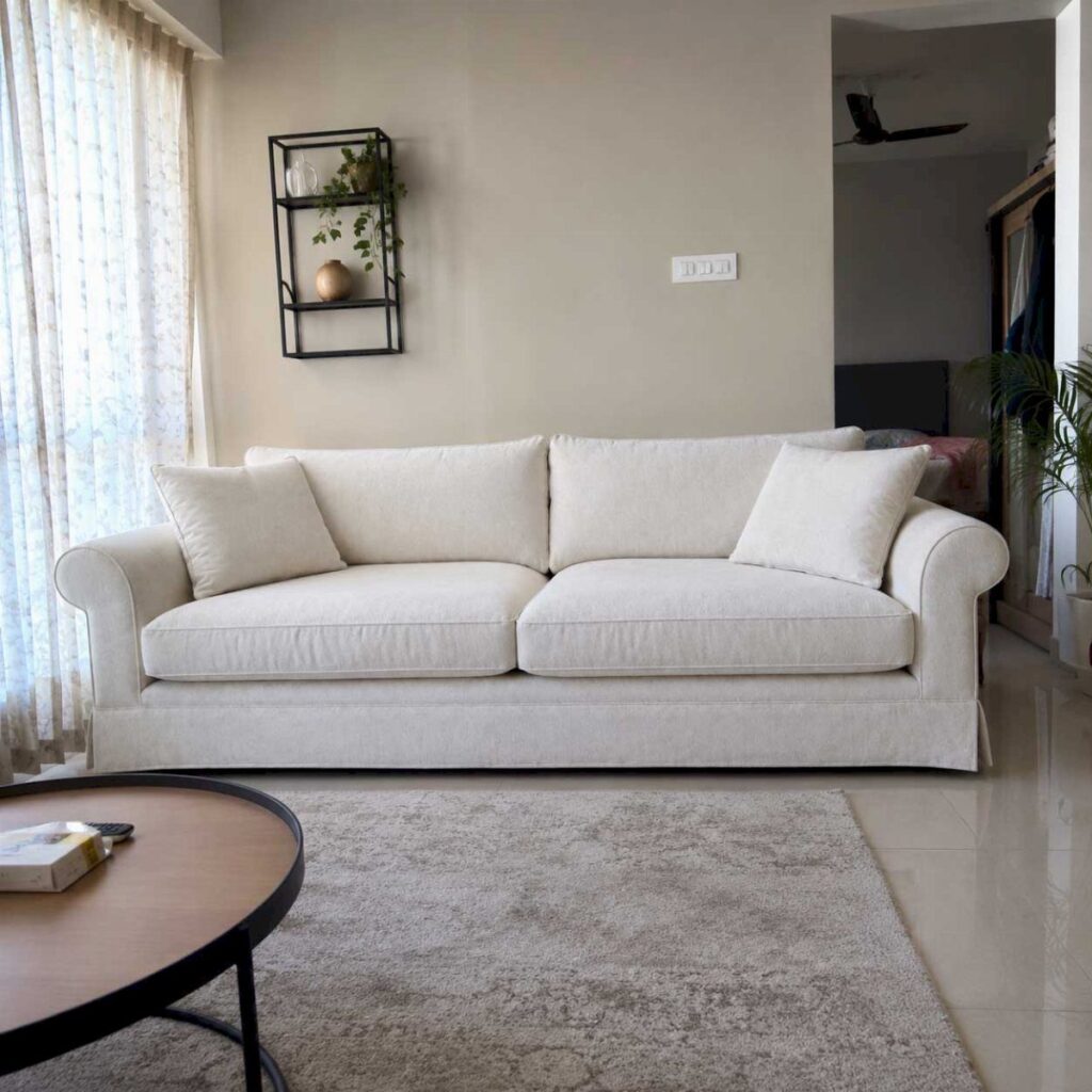 White fabric sofa with rolled arms in a neutral living room with rug.