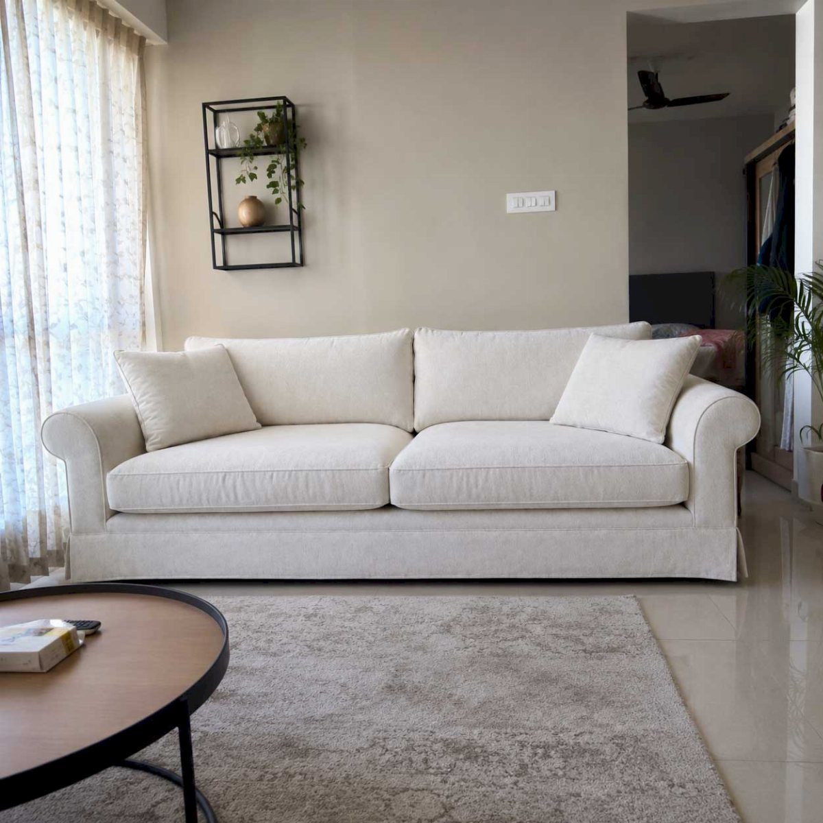 White fabric sofa with rolled arms in a neutral living room with rug.